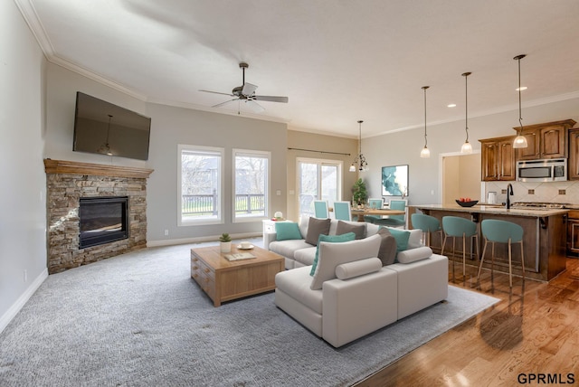 living room featuring a fireplace, crown molding, light hardwood / wood-style flooring, and ceiling fan with notable chandelier