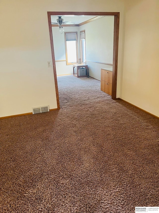 carpeted empty room with ceiling fan and ornamental molding