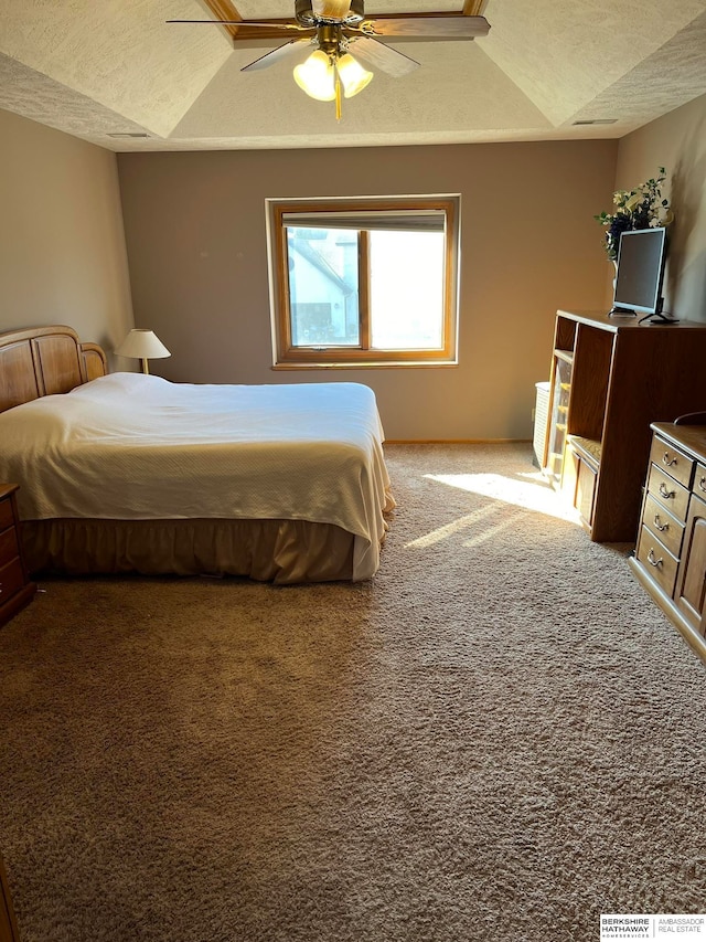 bedroom featuring a textured ceiling, carpet floors, a tray ceiling, and ceiling fan