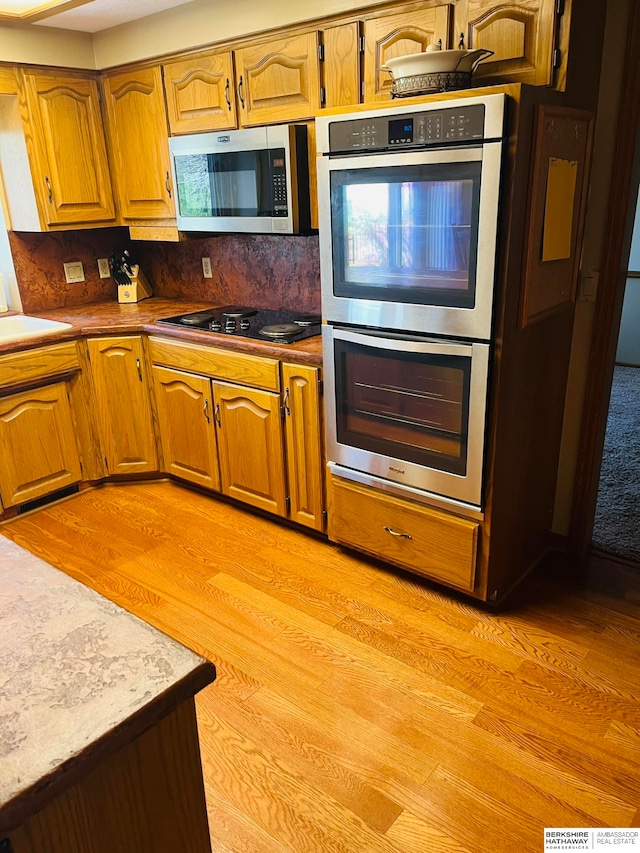 kitchen featuring light wood-type flooring, appliances with stainless steel finishes, and tasteful backsplash