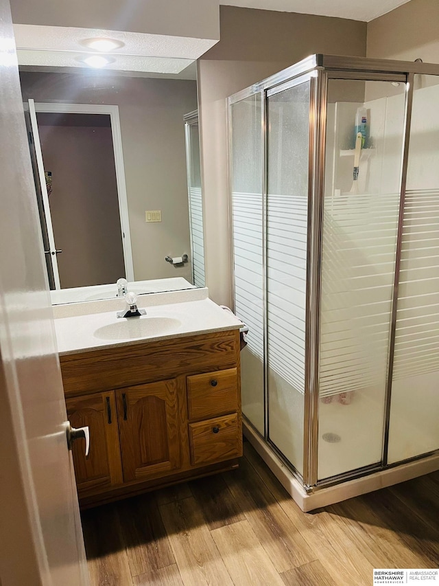 bathroom with hardwood / wood-style flooring, vanity, and a shower with door