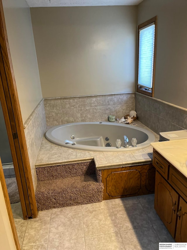 bathroom with tile patterned flooring, a relaxing tiled tub, and vanity