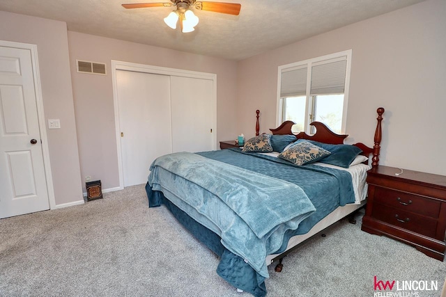 carpeted bedroom with ceiling fan, a textured ceiling, and a closet