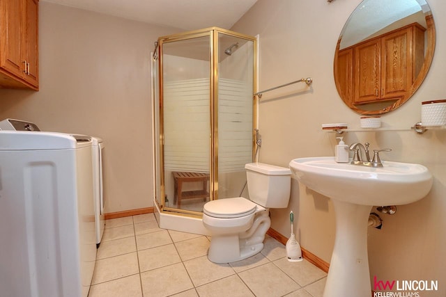 bathroom with tile patterned floors, toilet, washer / dryer, and a shower with shower door