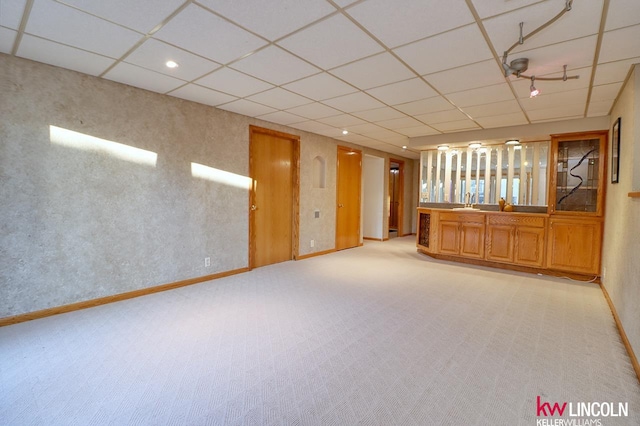 empty room featuring a drop ceiling, light colored carpet, and sink