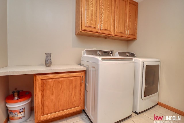 laundry room with cabinets, light tile patterned floors, and washing machine and clothes dryer