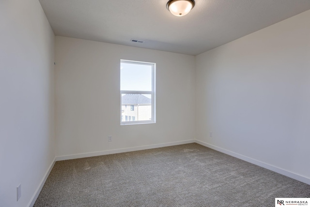 carpeted spare room with baseboards and visible vents