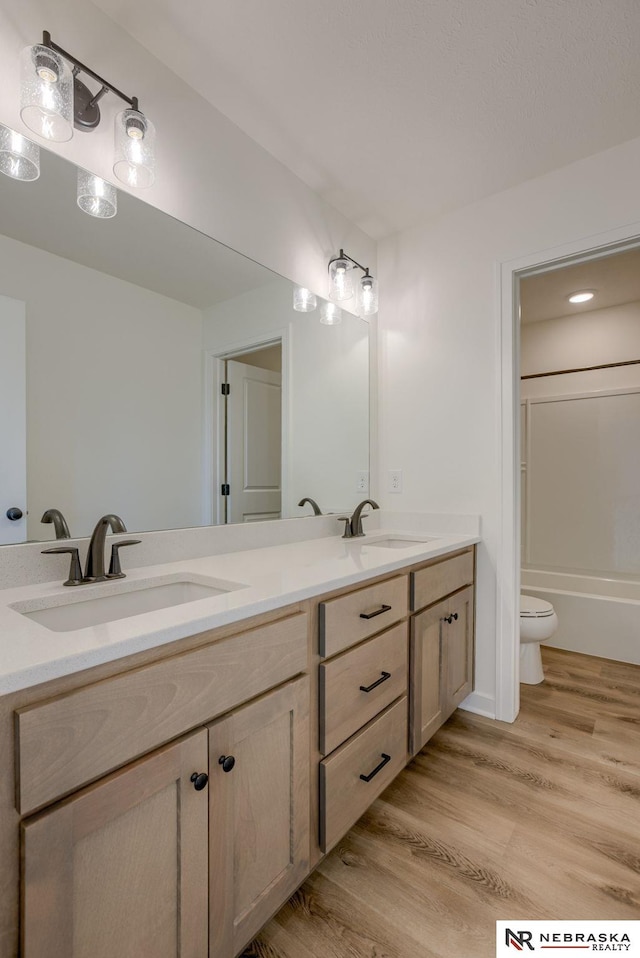 bathroom featuring a sink, toilet, wood finished floors, and double vanity