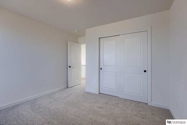 unfurnished bedroom featuring a closet and light carpet