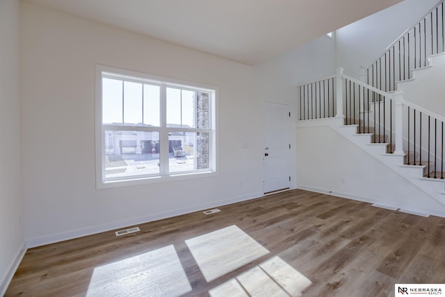 foyer entrance featuring visible vents, stairway, baseboards, and wood finished floors