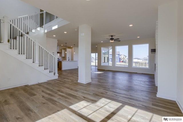 unfurnished living room with recessed lighting, wood finished floors, and baseboards