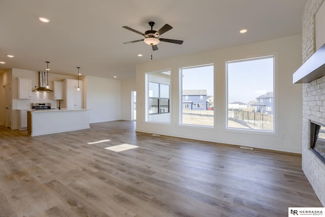 unfurnished living room featuring a wealth of natural light, light wood-style flooring, and a large fireplace