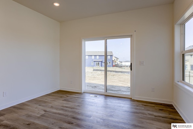 spare room with a wealth of natural light and dark hardwood / wood-style floors