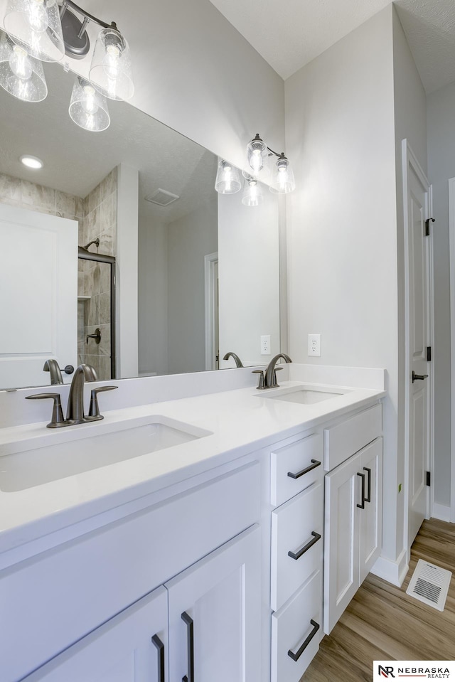 bathroom with vanity, a shower with shower door, and hardwood / wood-style floors