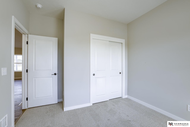 unfurnished bedroom with light carpet and a closet