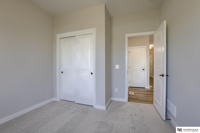 unfurnished bedroom with light colored carpet and a closet