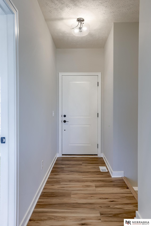 doorway to outside featuring a textured ceiling and light hardwood / wood-style flooring