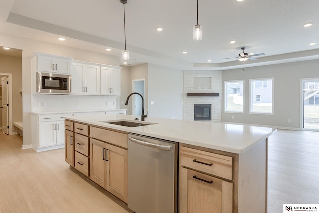 kitchen featuring decorative backsplash, appliances with stainless steel finishes, open floor plan, a tray ceiling, and a sink