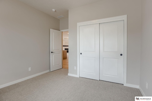 unfurnished bedroom featuring a closet, light colored carpet, visible vents, and baseboards