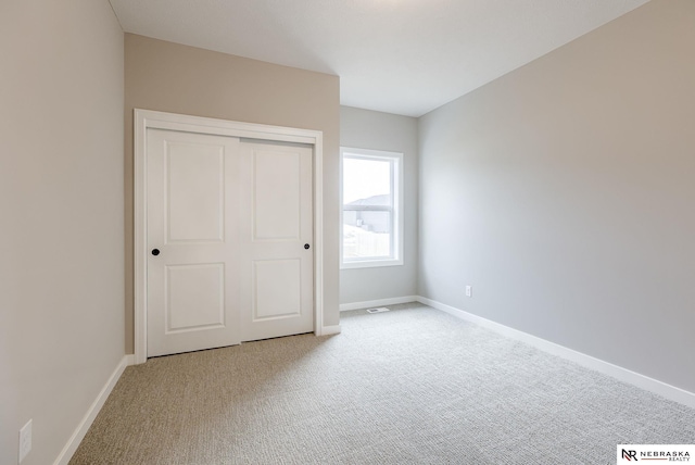 unfurnished bedroom featuring carpet, a closet, visible vents, and baseboards