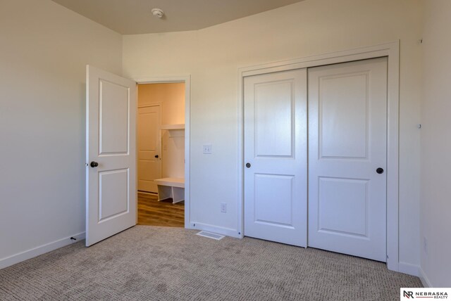 unfurnished bedroom with light colored carpet and a closet