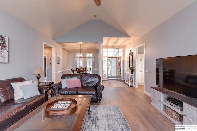 living room with decorative columns, light hardwood / wood-style flooring, lofted ceiling, and an inviting chandelier