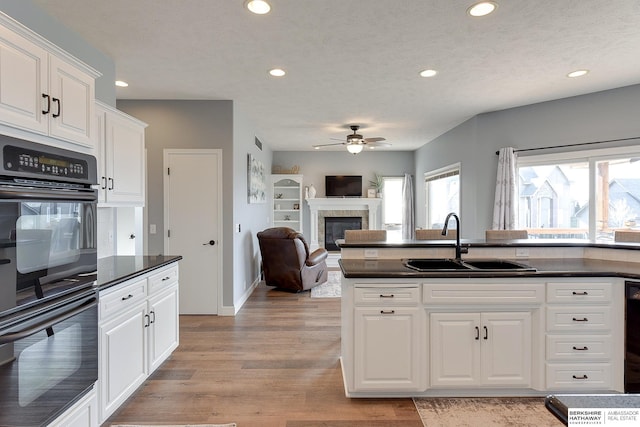 kitchen featuring a textured ceiling, ceiling fan, sink, light hardwood / wood-style floors, and white cabinetry