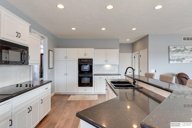 kitchen featuring black appliances, white cabinets, sink, and light hardwood / wood-style flooring