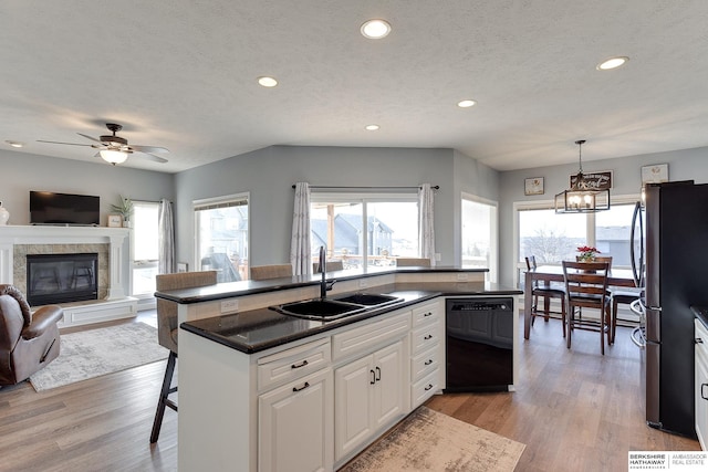 kitchen featuring stainless steel refrigerator, dishwasher, a kitchen breakfast bar, decorative light fixtures, and white cabinets