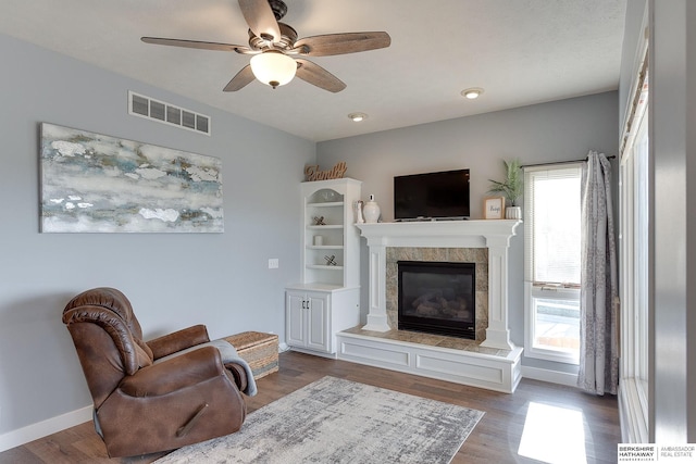 living room featuring hardwood / wood-style flooring, ceiling fan, a healthy amount of sunlight, and a tiled fireplace