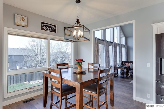 dining space with hardwood / wood-style floors, plenty of natural light, and an inviting chandelier