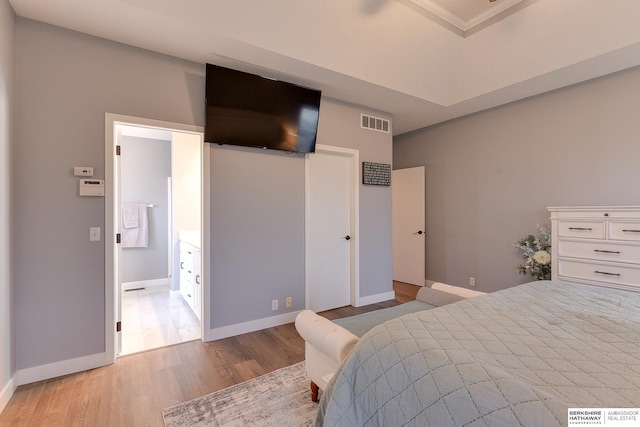 bedroom with ensuite bath and light wood-type flooring