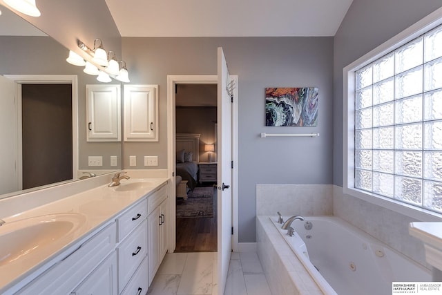 bathroom with tiled tub and vanity