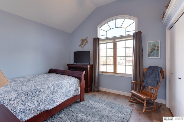 bedroom with a closet, vaulted ceiling, and hardwood / wood-style flooring