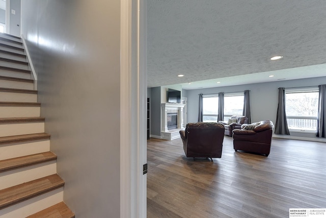 stairway featuring hardwood / wood-style floors, a textured ceiling, and a tile fireplace