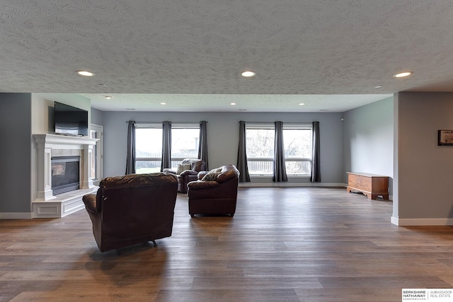 living room with a textured ceiling, dark wood-type flooring, and a tiled fireplace