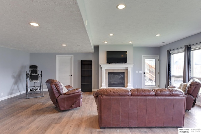 living room with a fireplace, a textured ceiling, and light hardwood / wood-style flooring