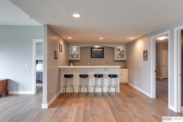 bar featuring light wood-type flooring and a textured ceiling