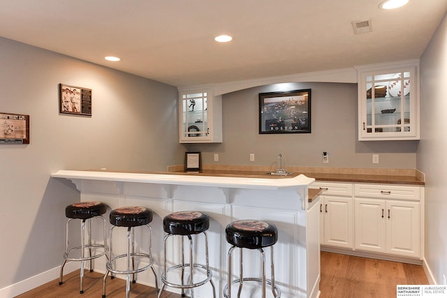 bar featuring white cabinets and light wood-type flooring