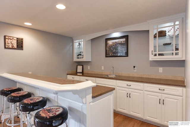 bar featuring white cabinets, light hardwood / wood-style floors, and sink