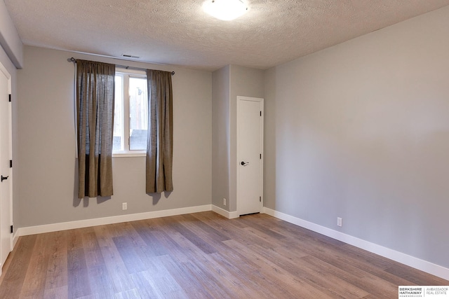 spare room with hardwood / wood-style floors and a textured ceiling