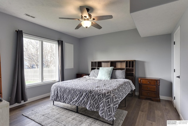 bedroom with ceiling fan, wood-type flooring, a textured ceiling, and multiple windows