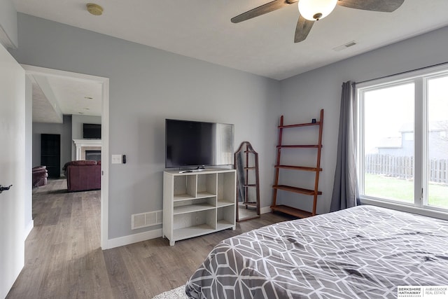 bedroom with multiple windows, ceiling fan, and wood-type flooring