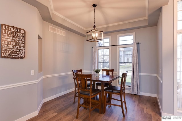 dining space featuring a tray ceiling, crown molding, dark hardwood / wood-style flooring, and a notable chandelier