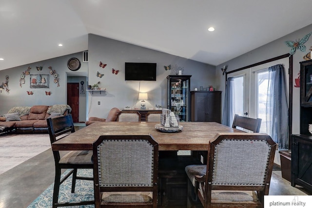 dining room featuring lofted ceiling, concrete flooring, and french doors