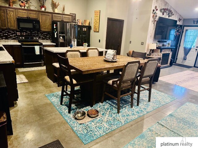 dining room with a stone fireplace, sink, and lofted ceiling