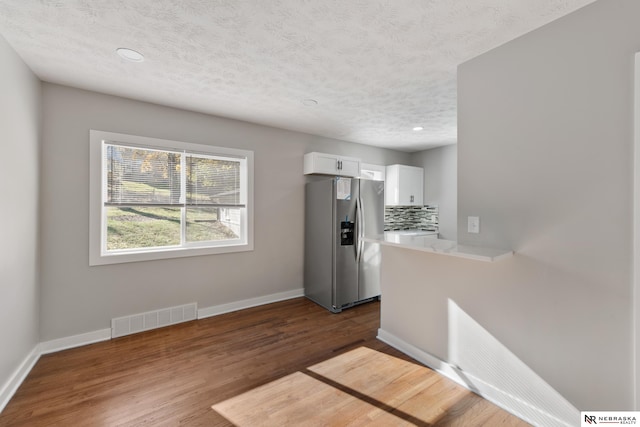 kitchen featuring decorative backsplash, stainless steel refrigerator with ice dispenser, dark hardwood / wood-style flooring, and white cabinetry