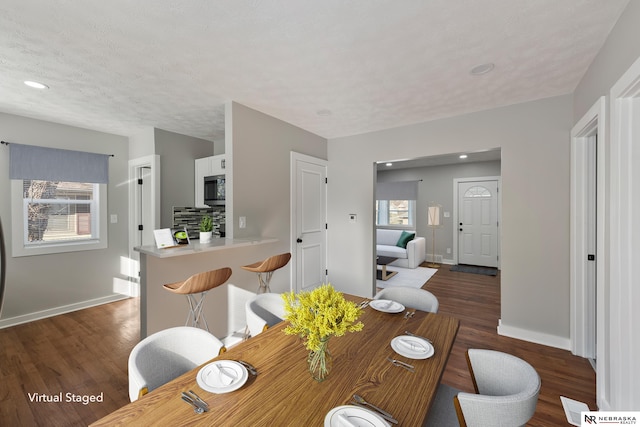 dining space featuring dark wood-type flooring and a textured ceiling