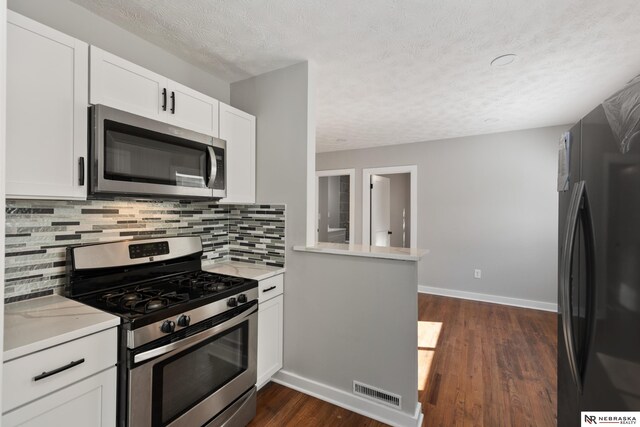 kitchen with kitchen peninsula, dark hardwood / wood-style flooring, stainless steel appliances, and white cabinets