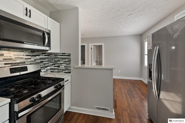 kitchen featuring kitchen peninsula, white cabinets, dark hardwood / wood-style floors, and appliances with stainless steel finishes